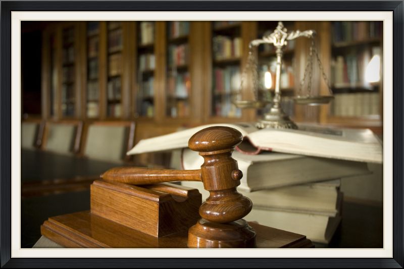 An image of a gavel, books and the scales of justice on a conference room table
