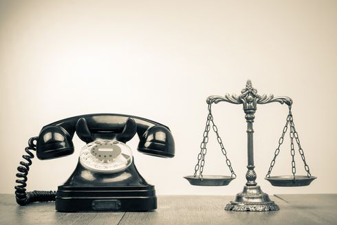 An image of an old fashioned rotary phone next to  the scales of justice
