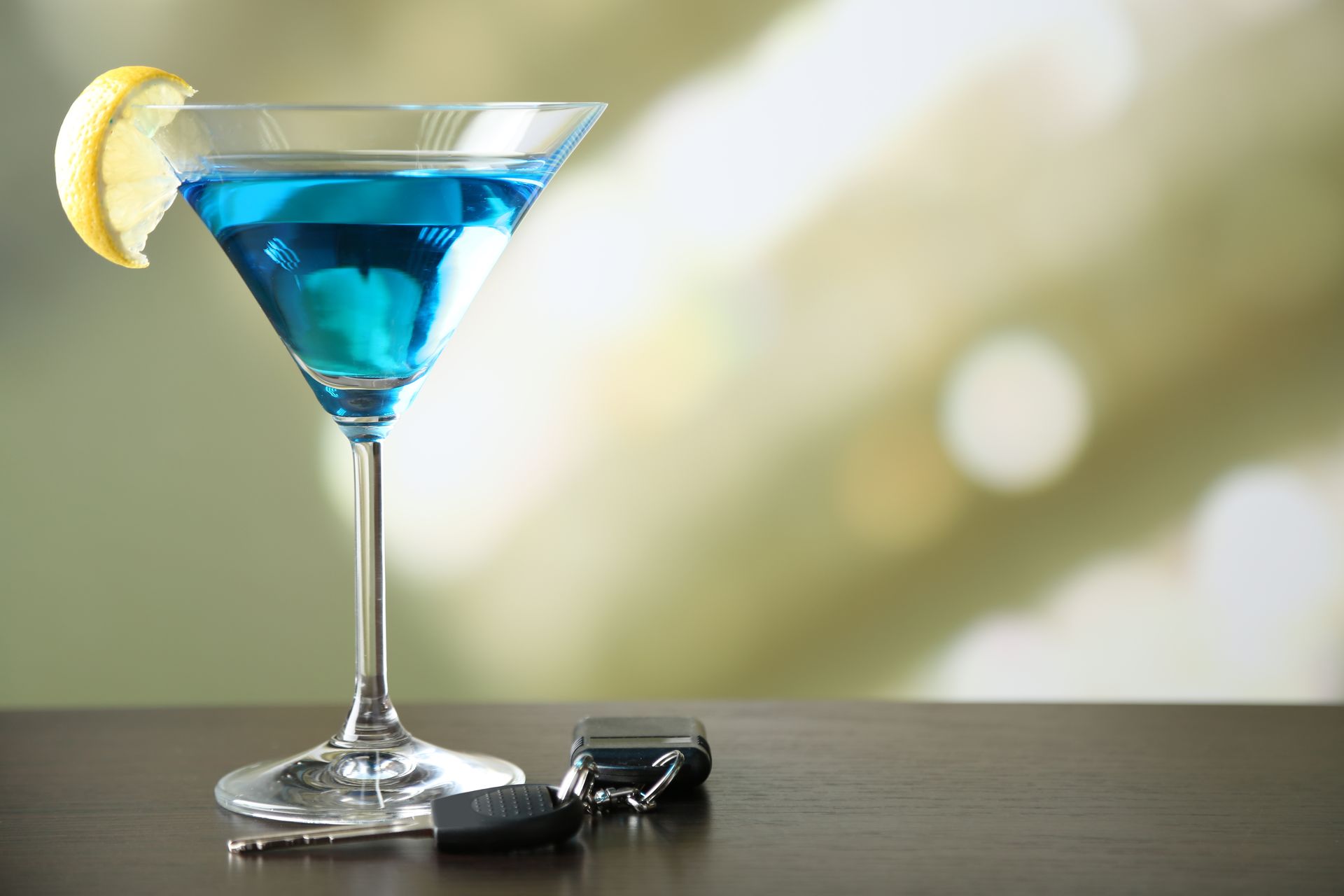 An Image of a car next to a blue martini with a lemon
