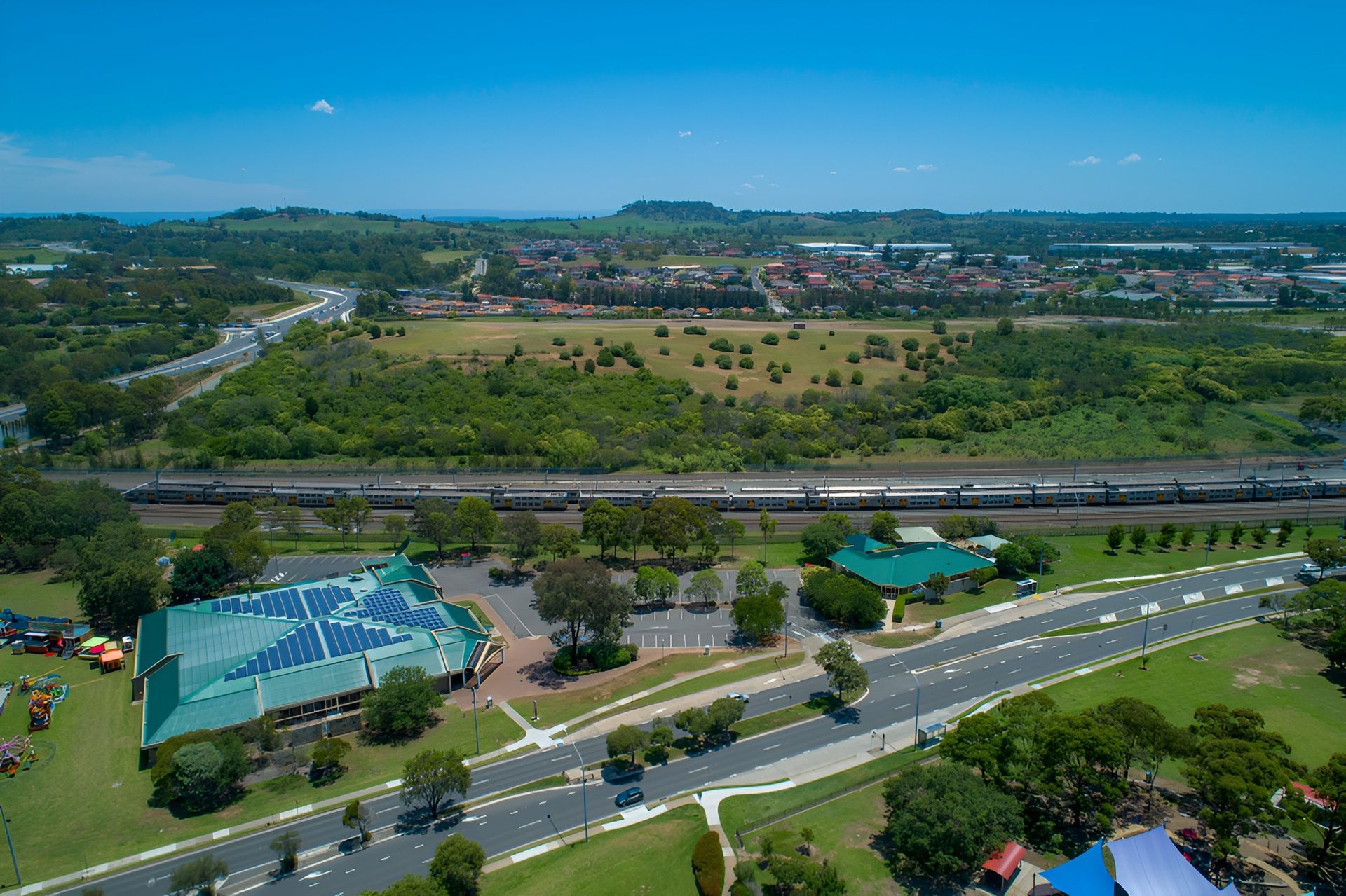 Aerial View: Train Track and Road Run Through a Town With Buildings — Affordable Underpinning Solutions In Campbelltown, NSW