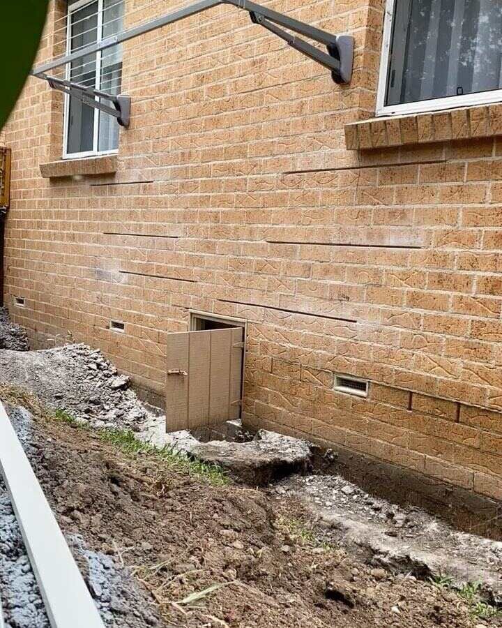A Brick Building With A Hole In The Ground In Front Of It — Affordable Underpinning Solutions In Shell Cove, NSW