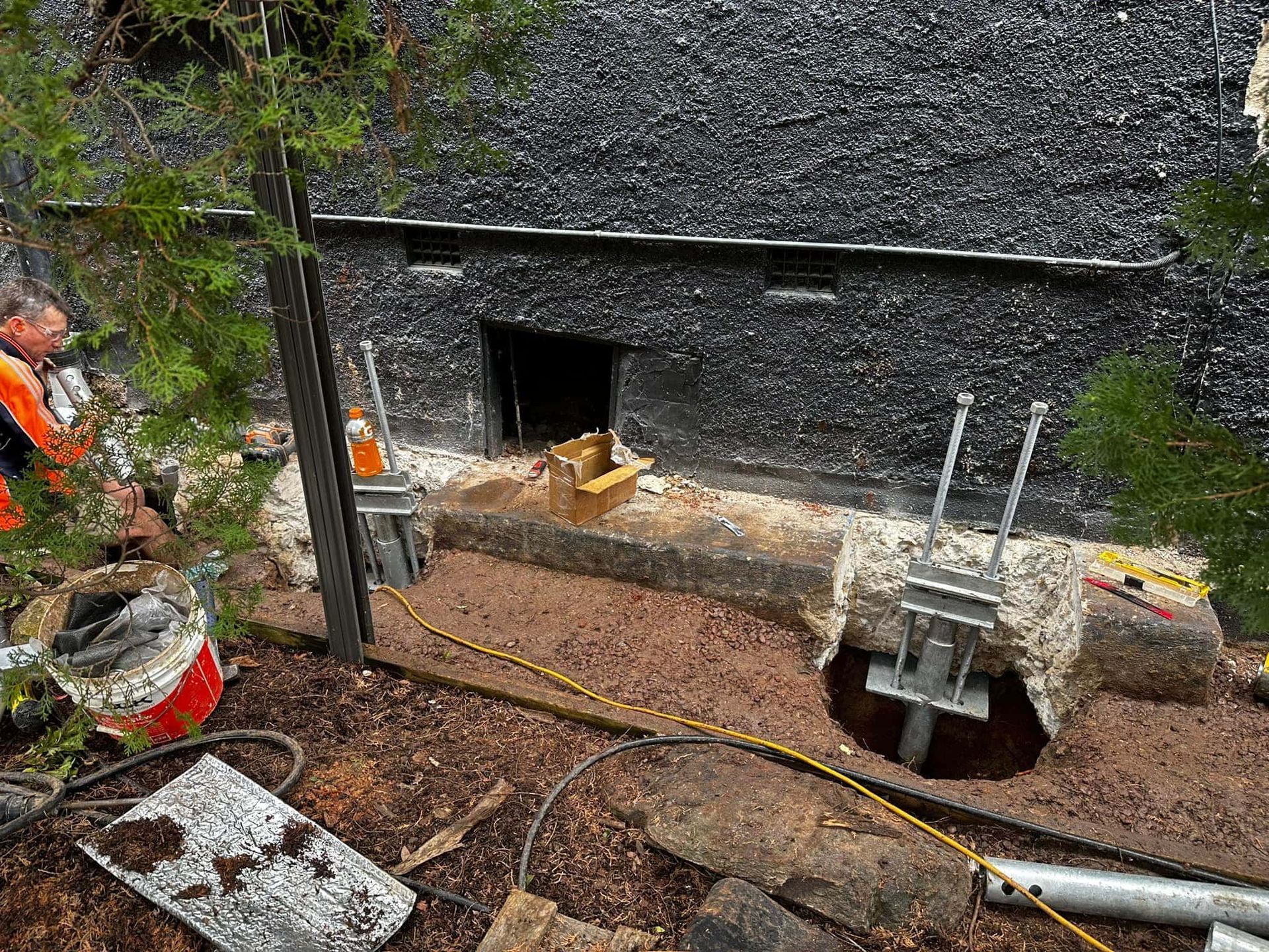 A Person Is Underpinning A Concrete Wall — Affordable Underpinning Solutions In Wollongong, NSW