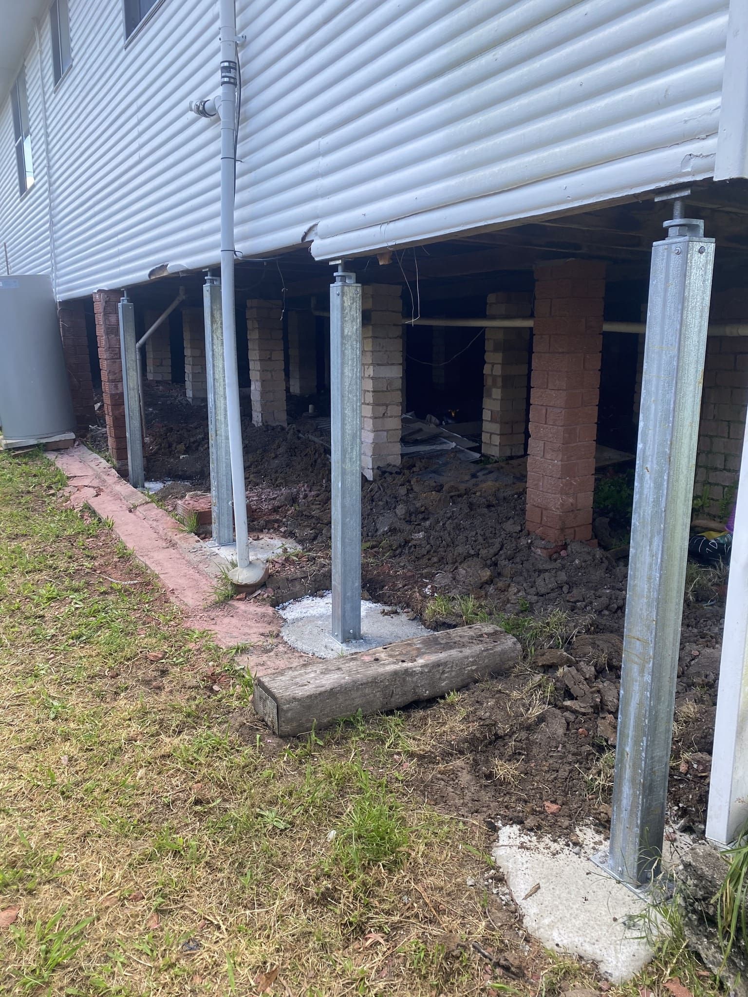House on Stilts With Steel Posts, Brick Supports, and Exposed Dirt — Affordable Underpinning Solutions In Bondi, NSW