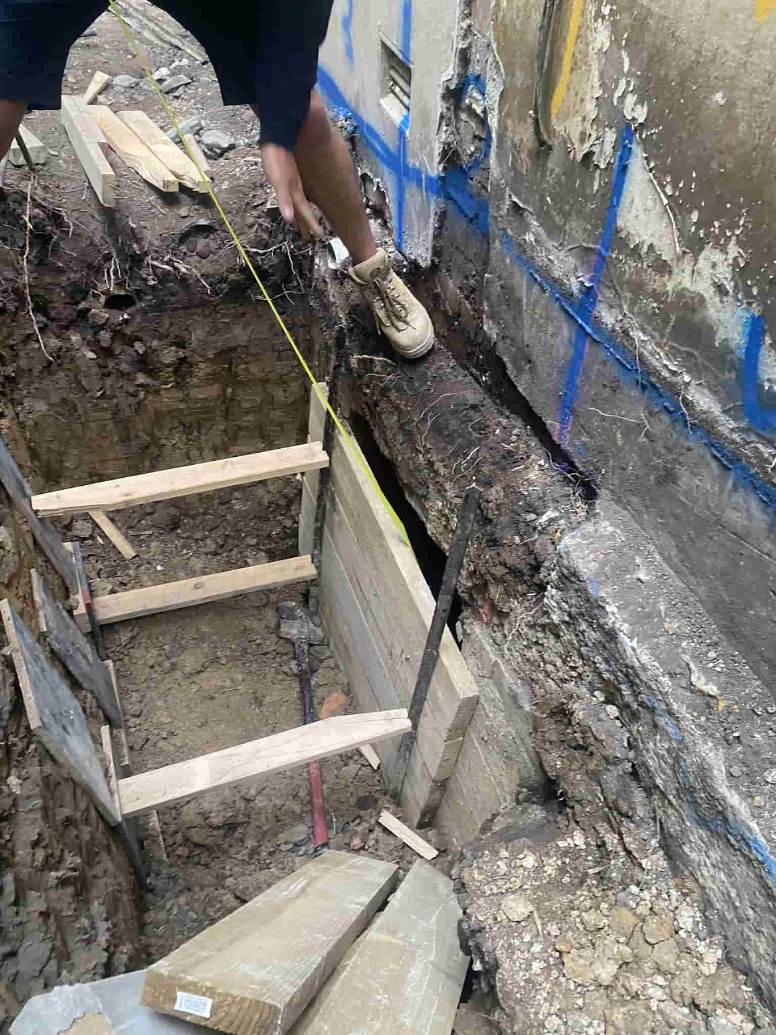 A man is measuring a hole in the ground with a tape measure — Affordable Underpinning Solutions In Shell Cove, NSW