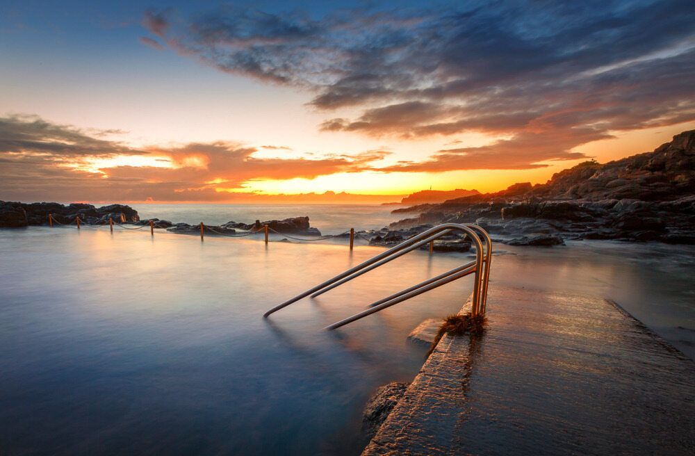 A Swimming Pool With Stairs Leading Into It At Sunset — Affordable Underpinning Solutions In Kiama, NSW