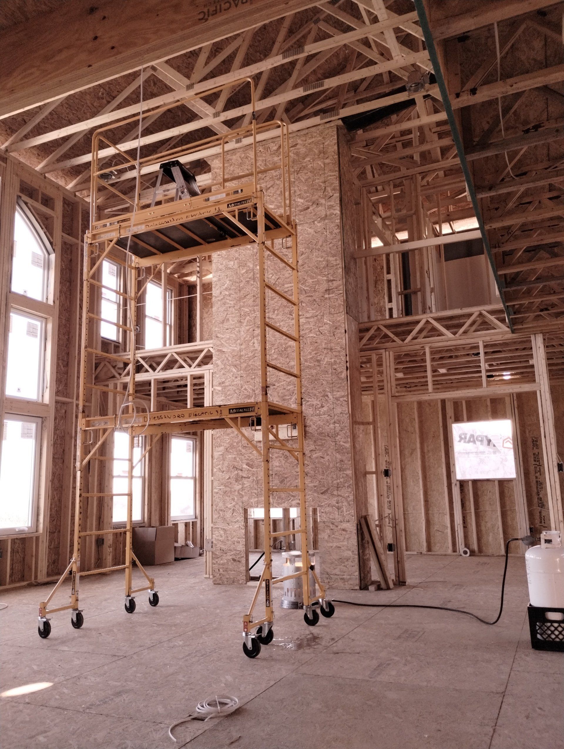 A large room under construction with scaffolding and windows.