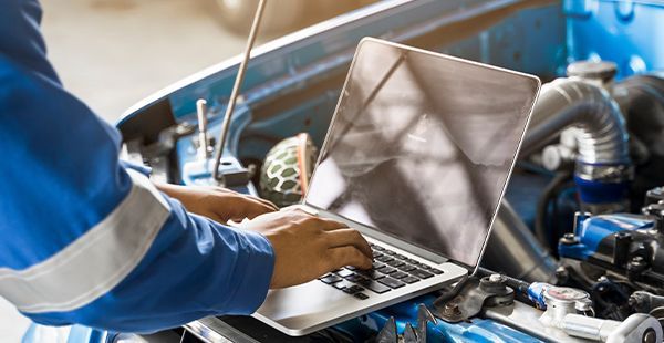 Working on laptop with car hood open | Olmsted Auto Care