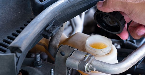 Man holding cap of brake fluid | Olmsted Auto Care