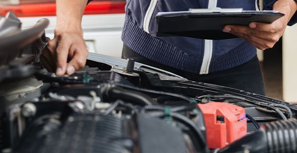Man inspecting under hood of vehicle | Olmsted Auto Care
