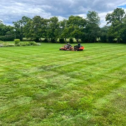 NEK Tree Workz two orange lawn tractors parked in the middle of a freshly manicured lawn