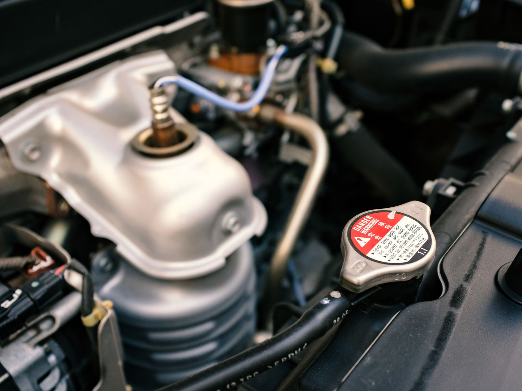 Close-up of a car engine bay with a silver strut mount and radiator cap.