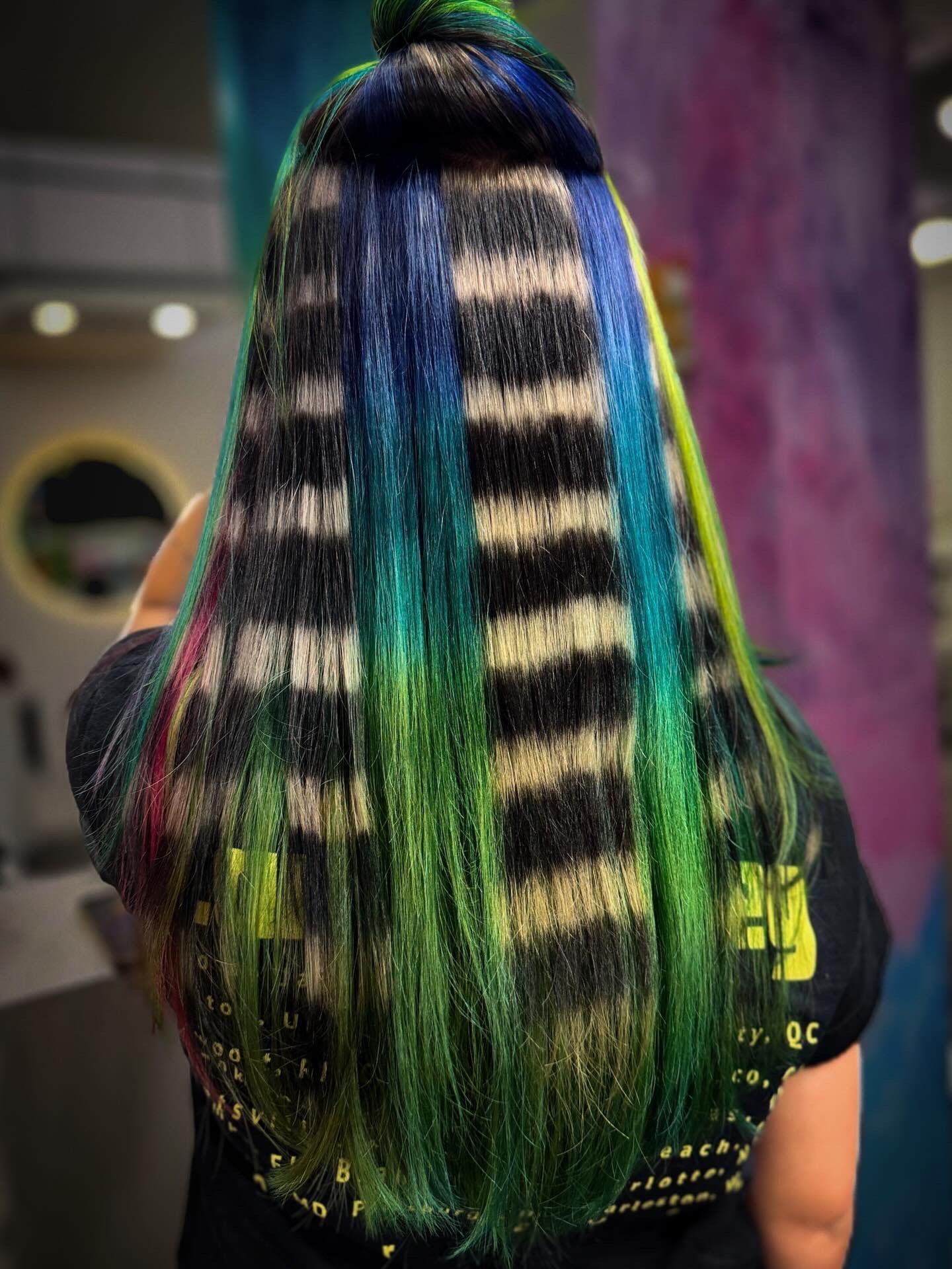 Woman's long, colorful hair styled with black stripes. Blue, green, and pink highlights.