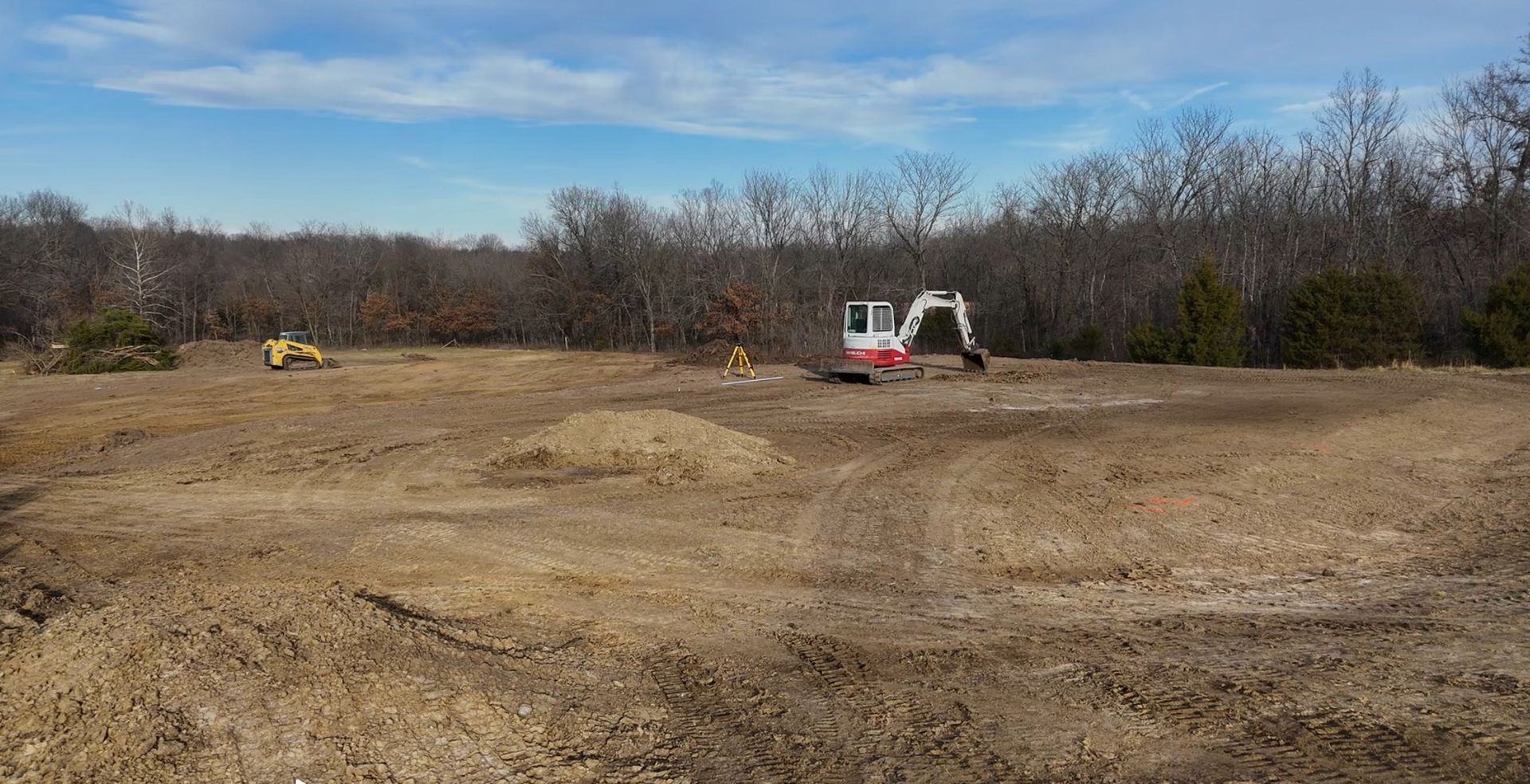 A yellow excavator is sitting on top of a pile of dirt.