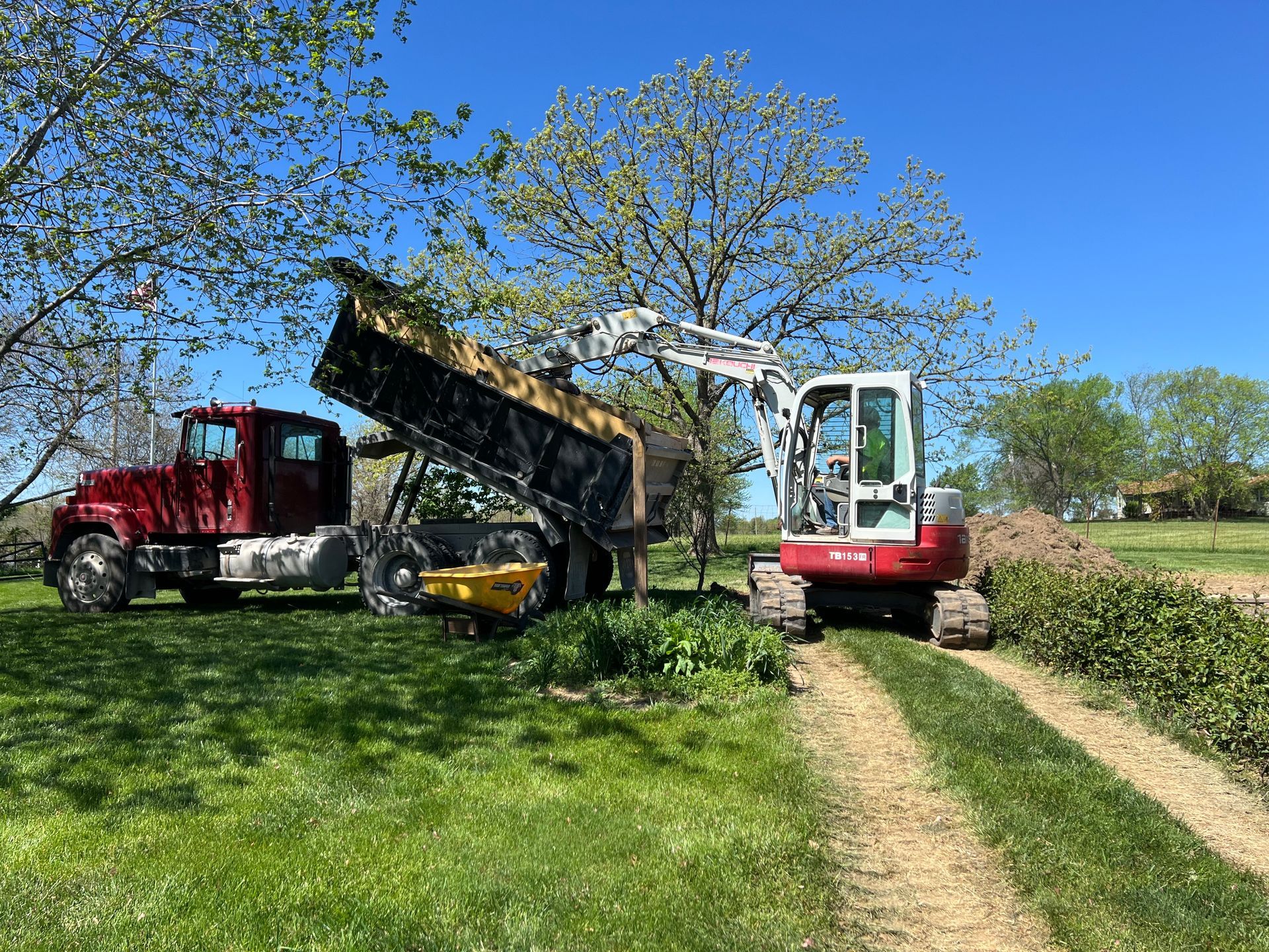 A dump truck is being loaded with sand by a bulldozer.