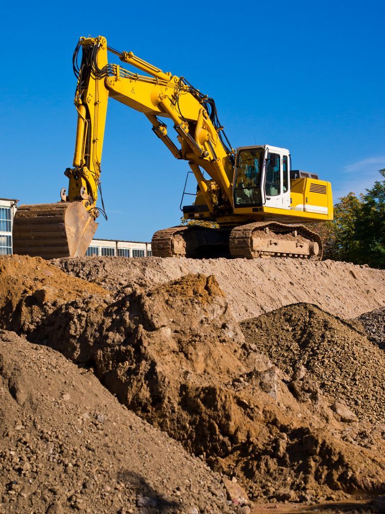 A yellow excavator is sitting on top of a pile of dirt.