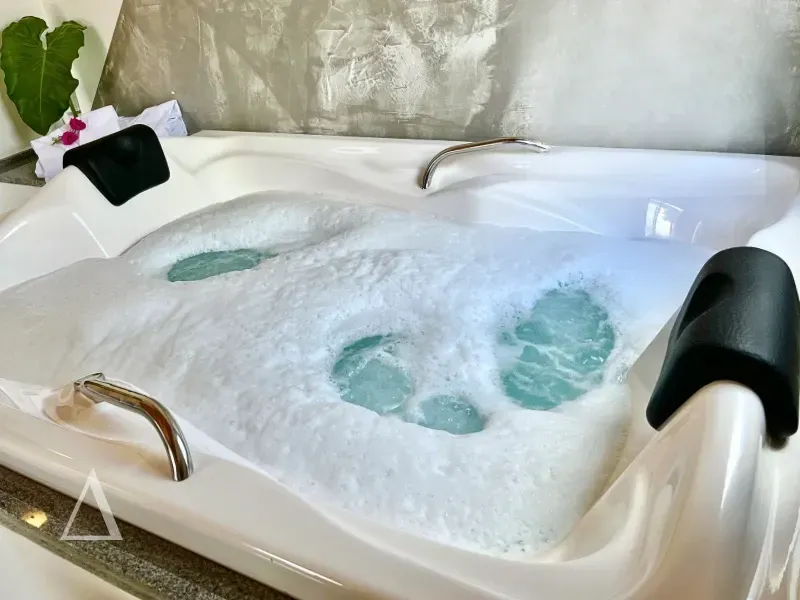 Banheira de hidromassagem com espuma e jatos de água na Quattuor Cabanas. Detalhe para o encosto de cabeça confortável e ambiente relaxante para casais em São Miguel do Gostoso.