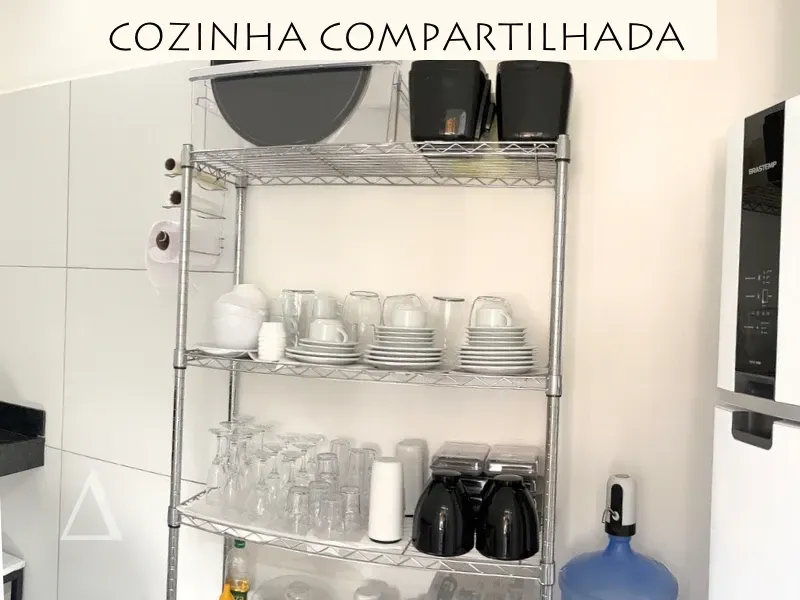 Cozinha compartilhada na Quattuor Cabanas em São Miguel do Gostoso, mostrando prateleira organizada com louças, copos, eletrodomésticos e geladeira.