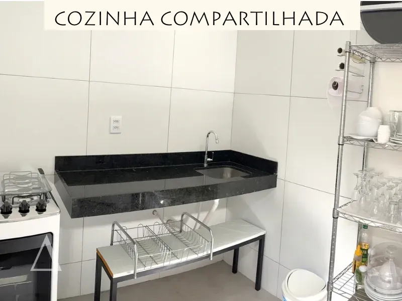 Vista da cozinha compartilhada na Quattuor Cabanas em São Miguel do Gostoso, com bancada de granito preto, pia, fogão e área de apoio organizada.