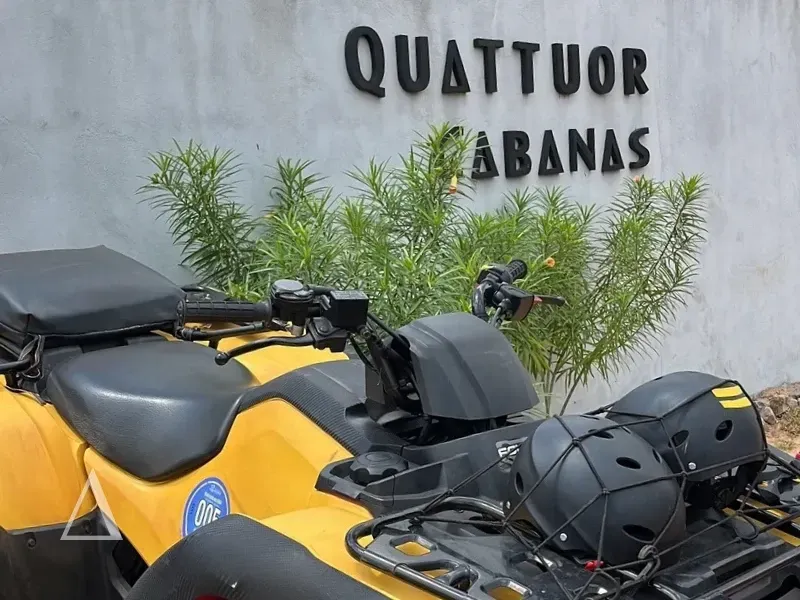 Detalhe de um quadriciclo amarelo com capacetes em frente à fachada da Quattuor Cabanas em São Miguel do Gostoso.