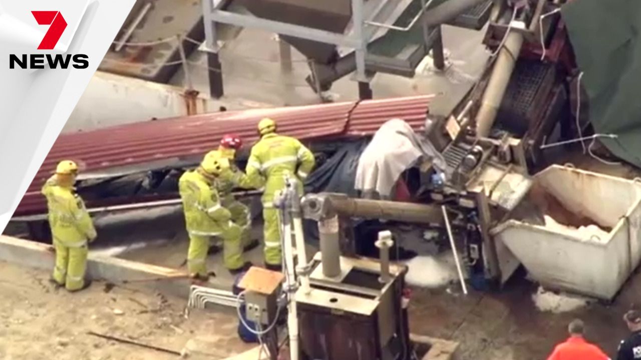 Two men loading a yellow trash bag into a van at night.