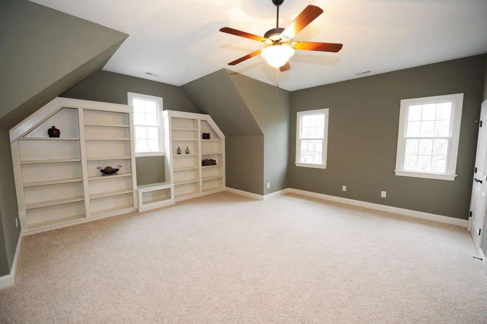 An empty room with a ceiling fan and shelves