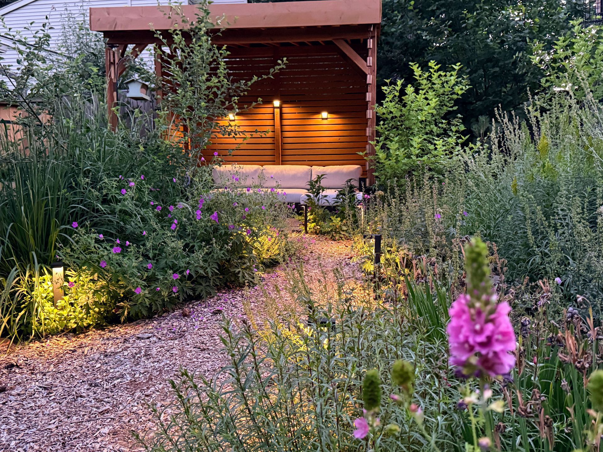 native plant habitat garden with bark chip pathway and green roof shade structure 