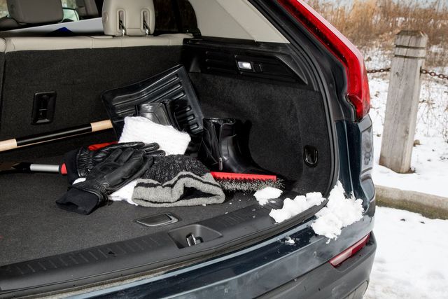 Winter emergency kit items in car trunk including blanket, food, and tools