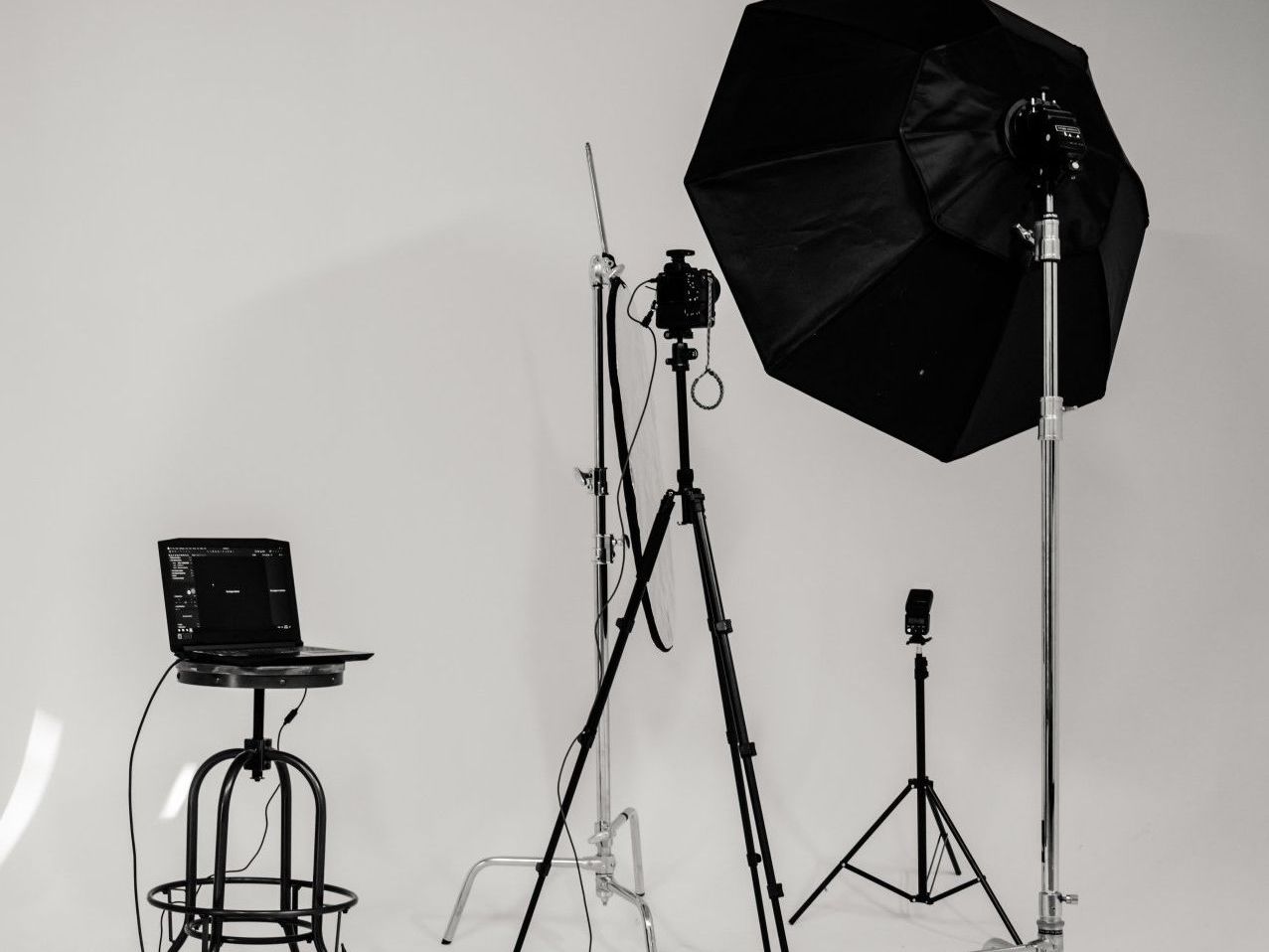 A black and white photo of a photo studio with a laptop on a stand