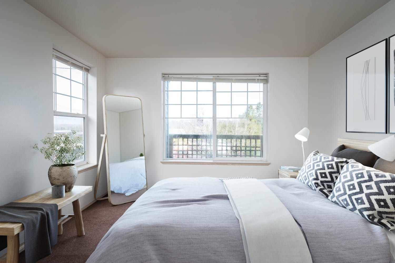 Bedroom with bed, mirror, two windows, art, bench, and neutral color scheme.