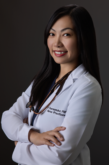 A woman in a lab coat with a stethoscope around her neck is standing with her arms crossed.