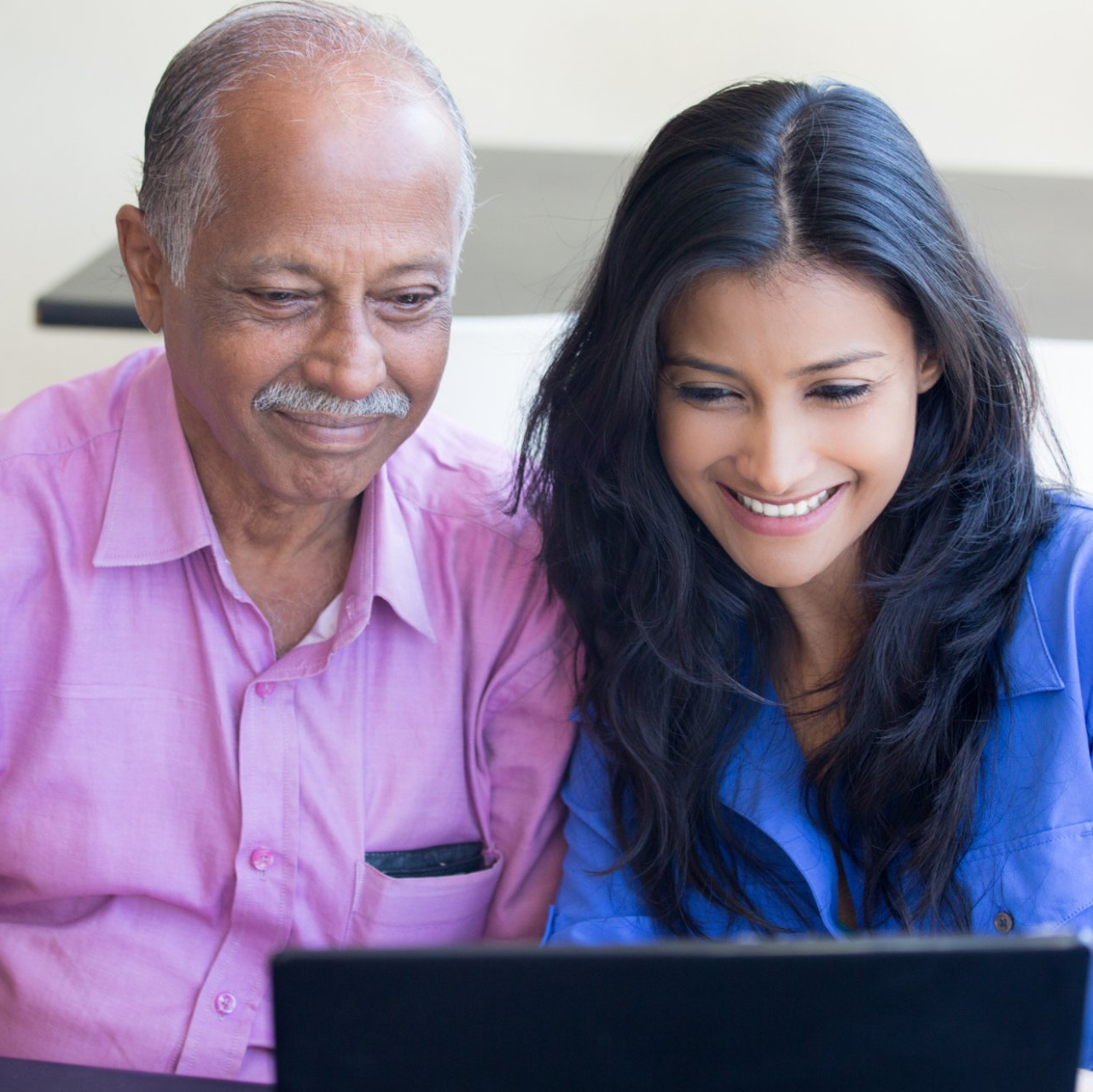 elderly indian man and adult daughter using computer together