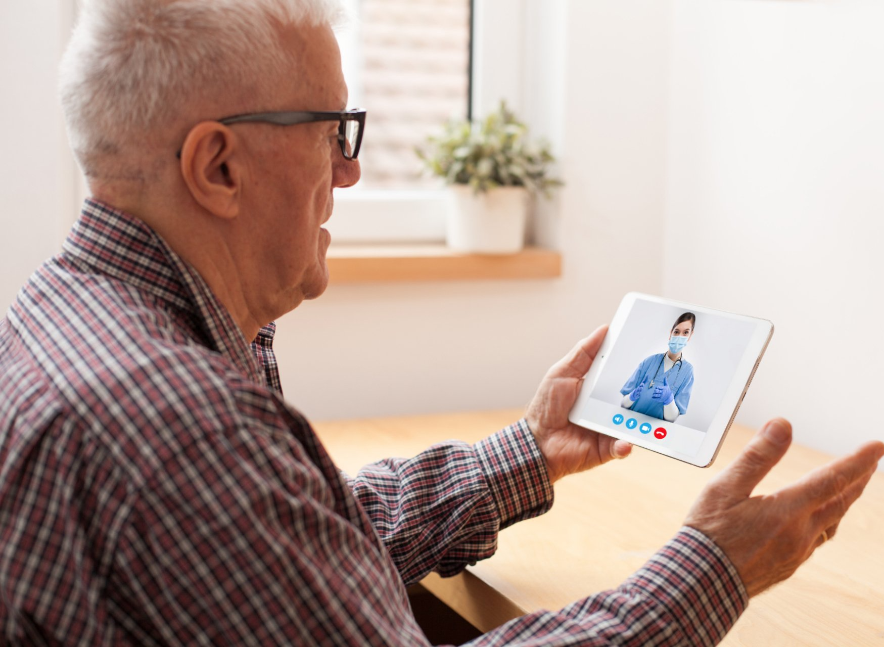 elderly man holding tablet during telehealth video call
