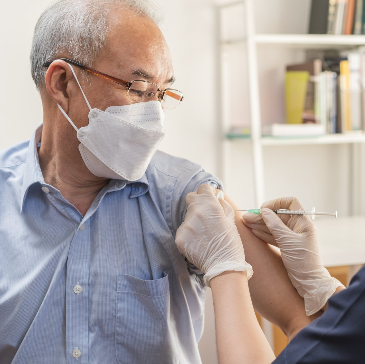elderly asian man receives vaccine injection in upper arm