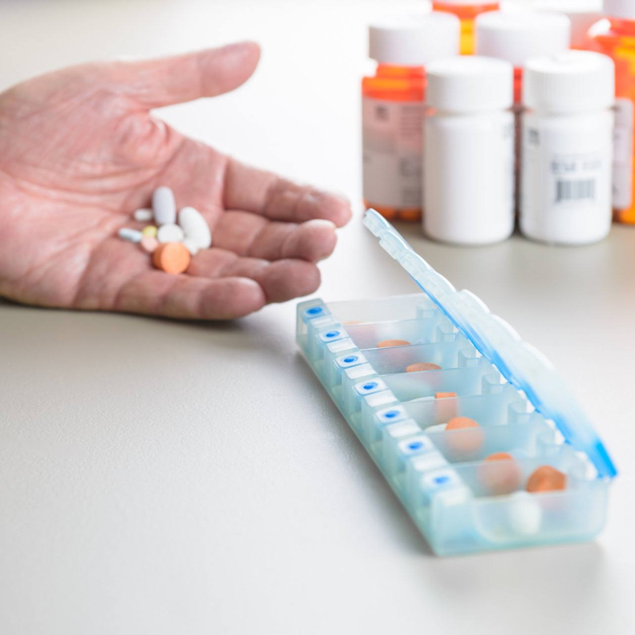 closeup of elderly person sorting medications into divided box
