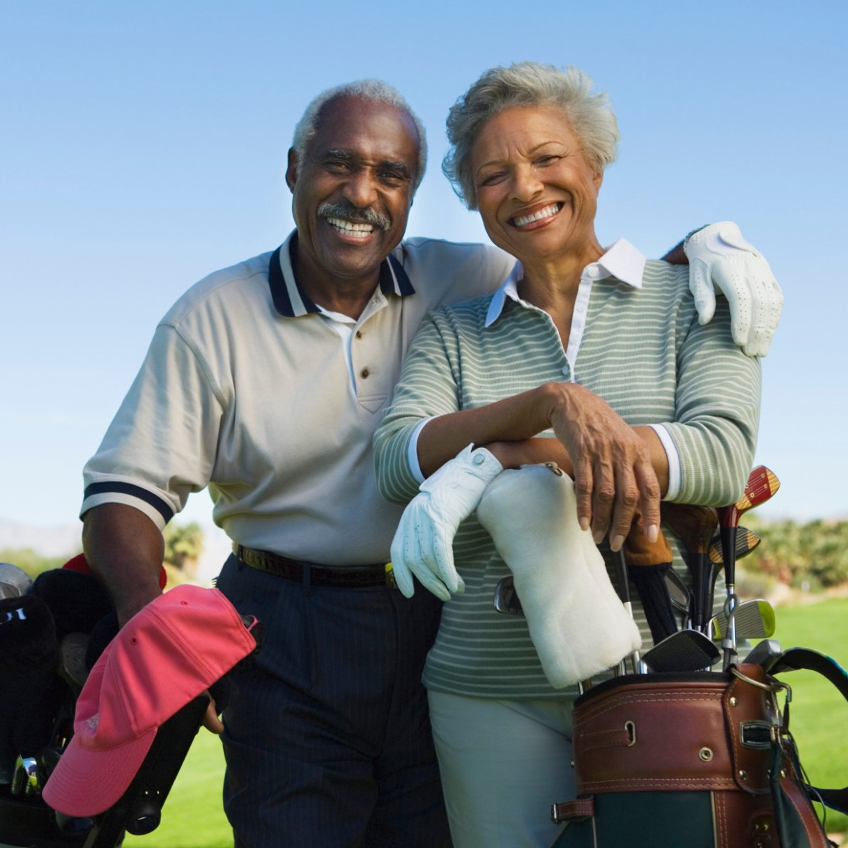 elderly black couple posing with golf gear