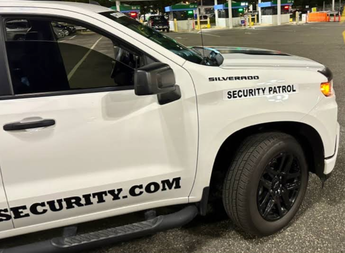 White security patrol truck at a gas station with black wheels and decals. 