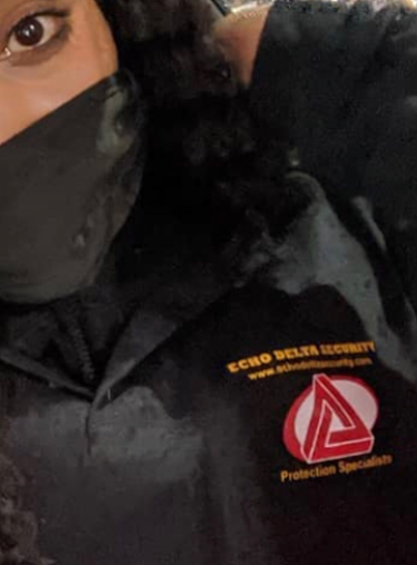 Person wearing a black mask and Echo Delta Security shirt with logo.