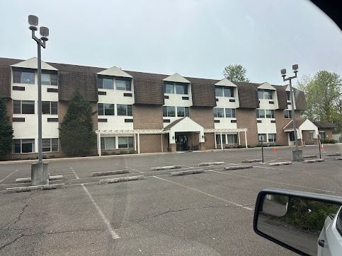 Large brick building with brown roof and parking lot.