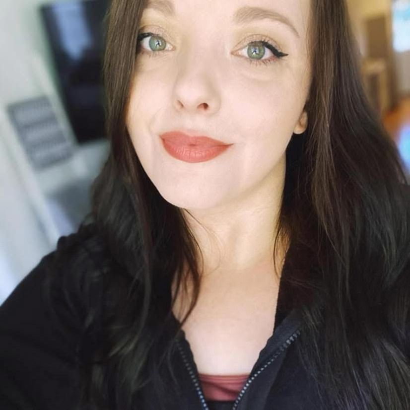 A close up of a woman 's face wearing a black jacket and red lipstick.