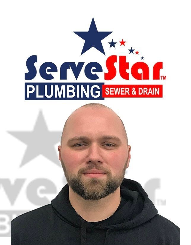 A man with a beard is standing in front of a logo for servestar plumbing