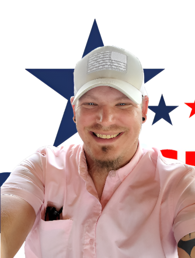 A man wearing a hat and a pink shirt is smiling in front of an american flag