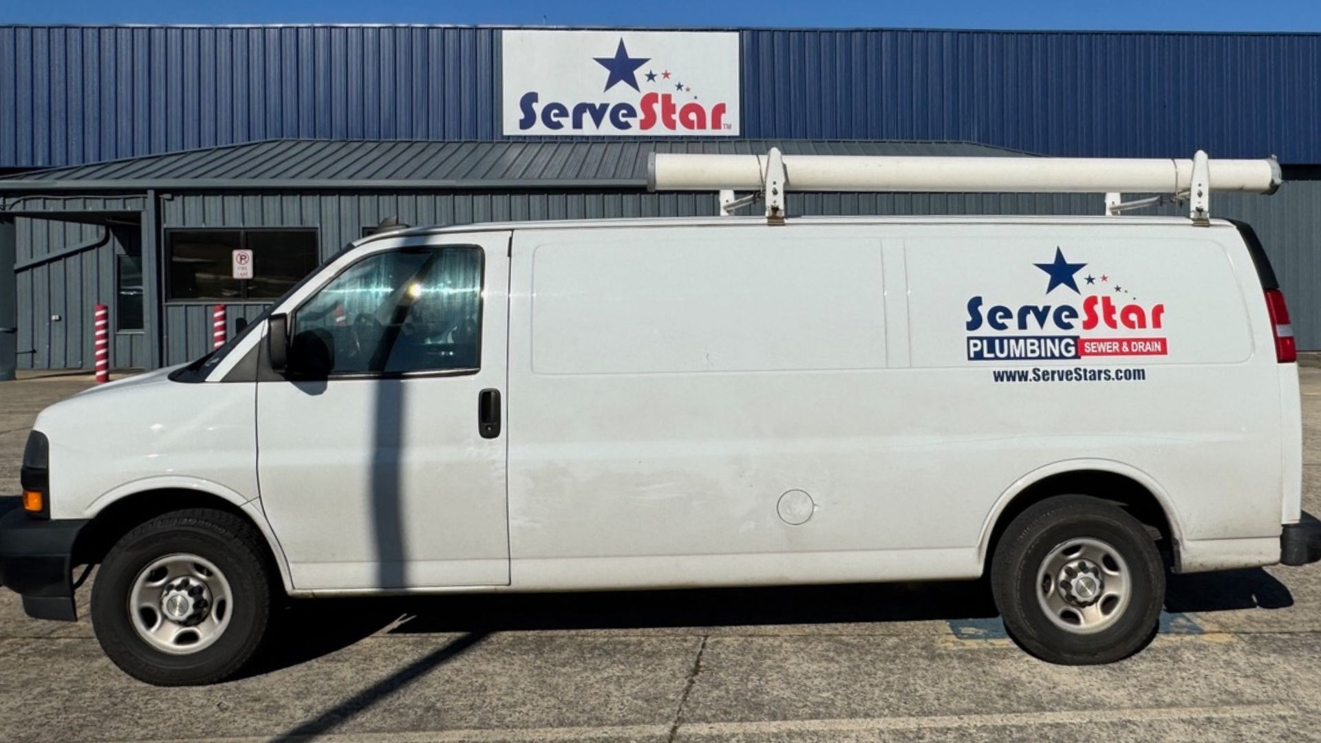 A white van is parked in front of a building that says servestar