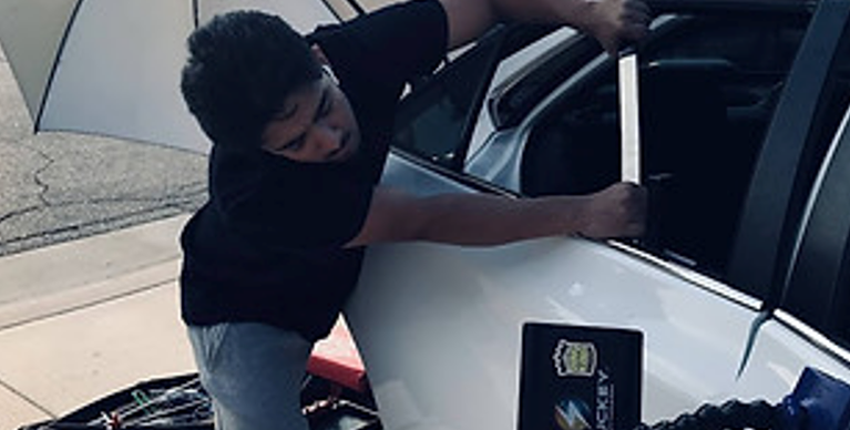 A Man Is Working On The Side Of A White Car – Menifee, CA – Push N Pull Paintless