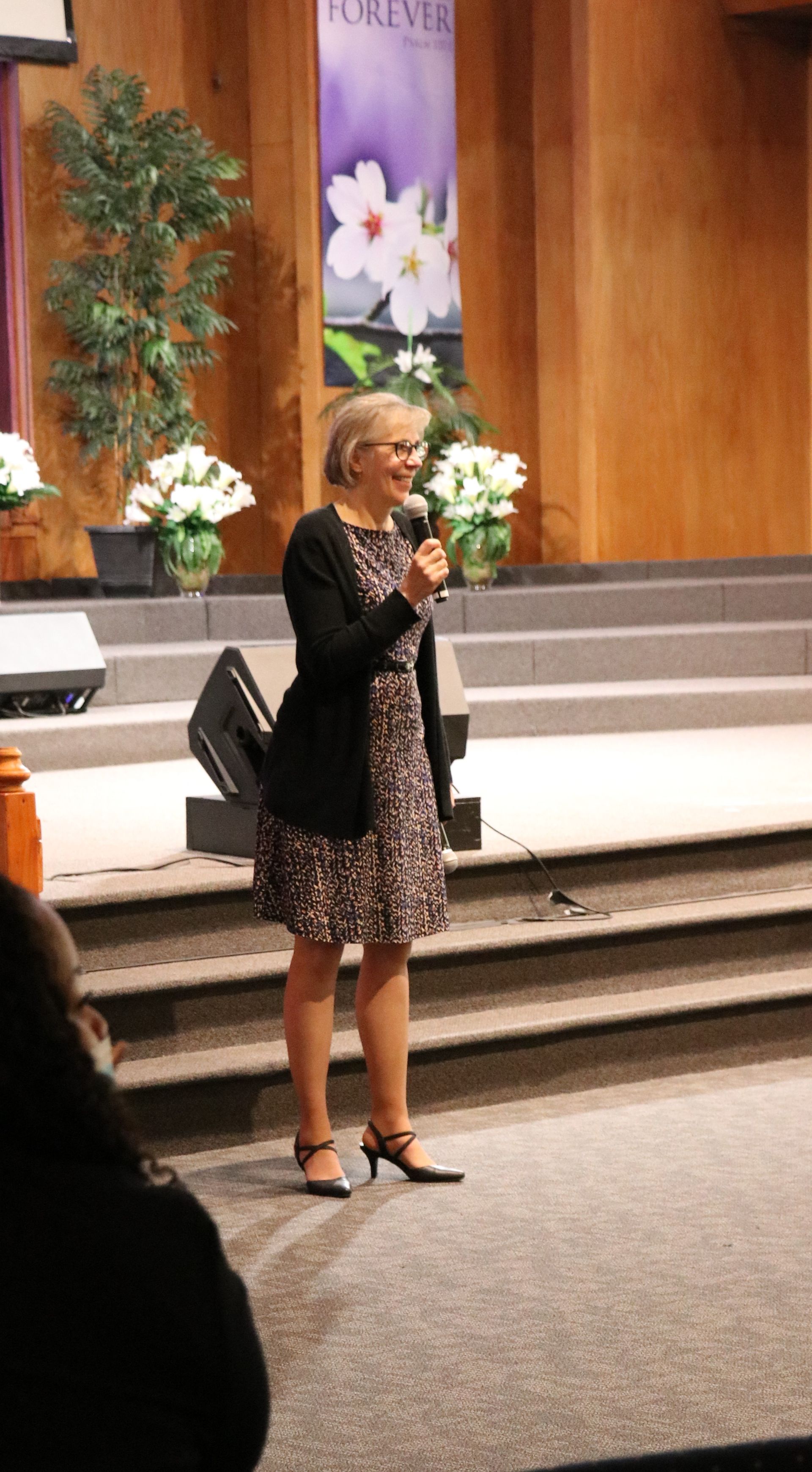 Woman speaking into a microphone on a stage.