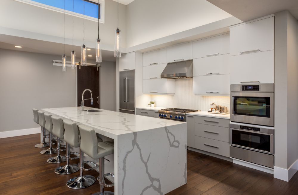 Kitchen With a Island, White Cabinets, Stainless Appliances, and Wood Floors — Affordable Tiles and Pavers In Morisset, NSW