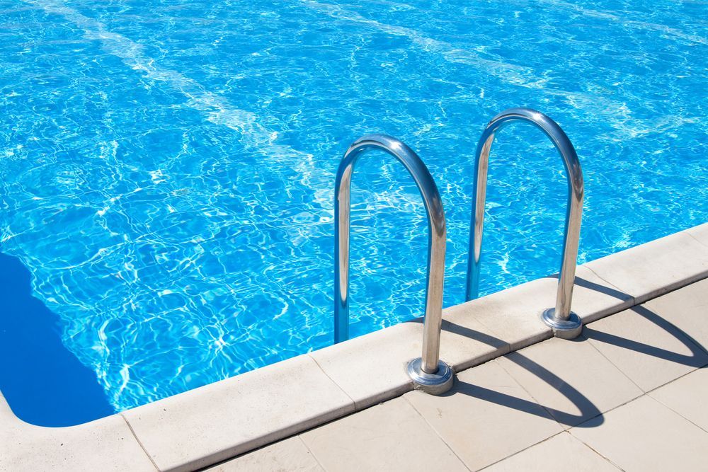 Blue Swimming Pool With Stainless Steel Handrails on the Edge — Affordable Tiles and Pavers In Morisset, NSW