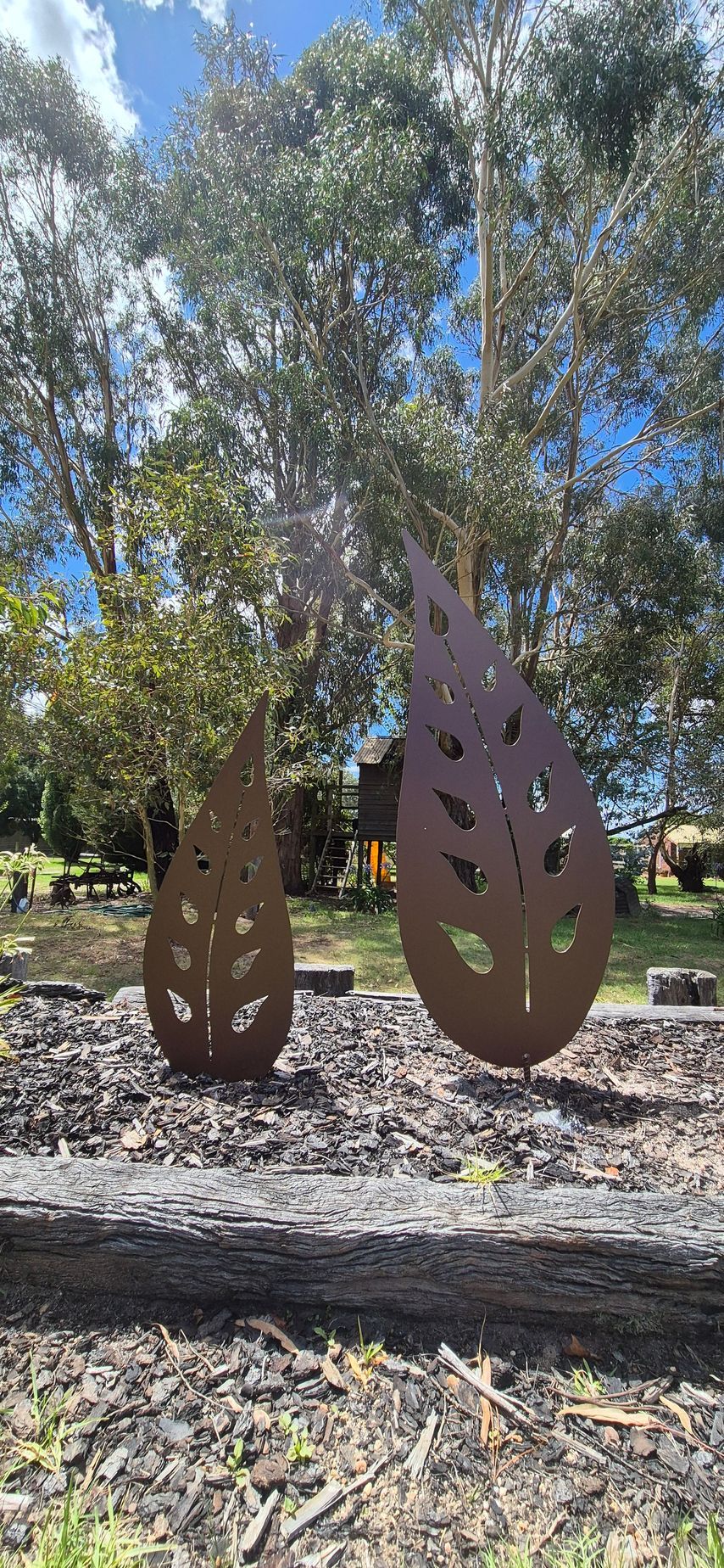 A couple of metal sculptures in the shape of leaves in a park.