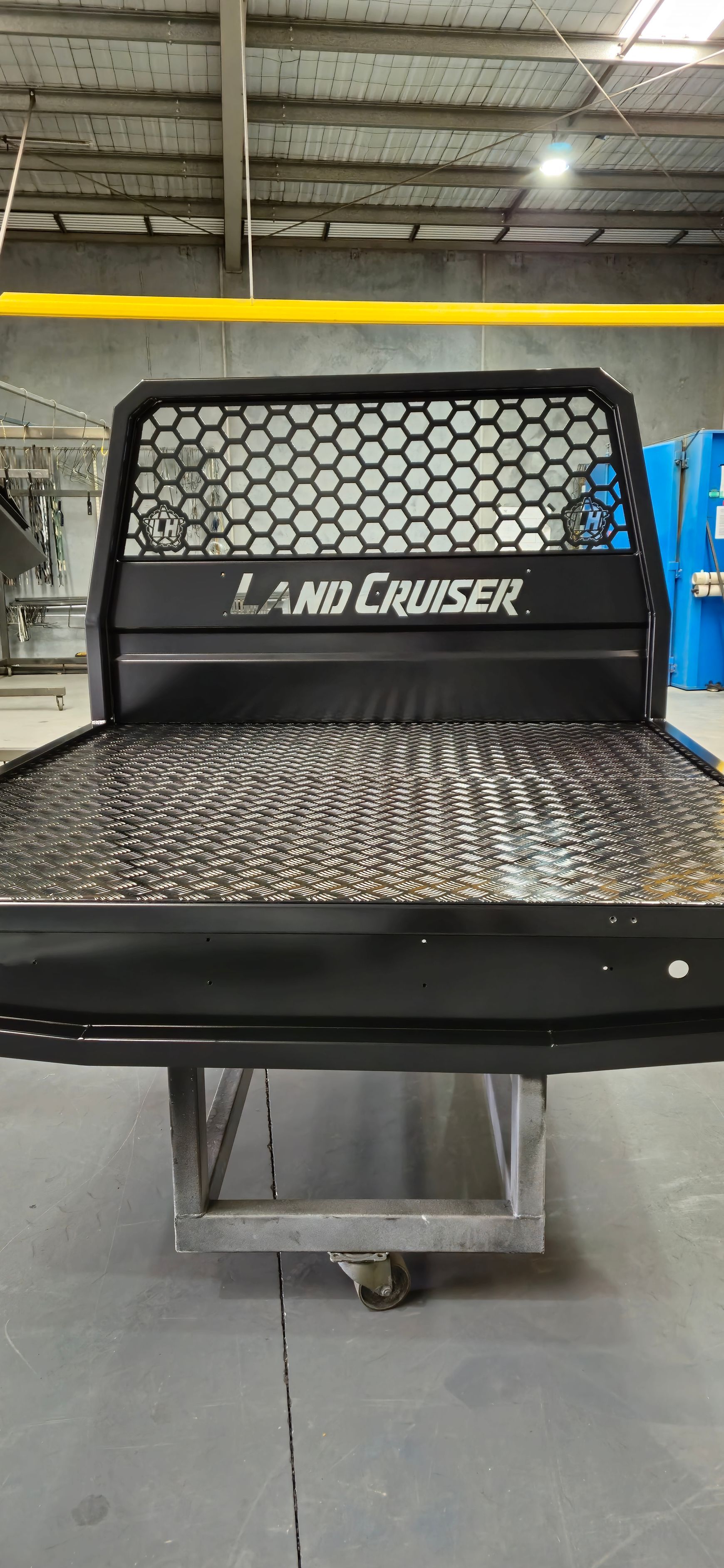 The back of a land cruiser truck is sitting on a cart in a warehouse.