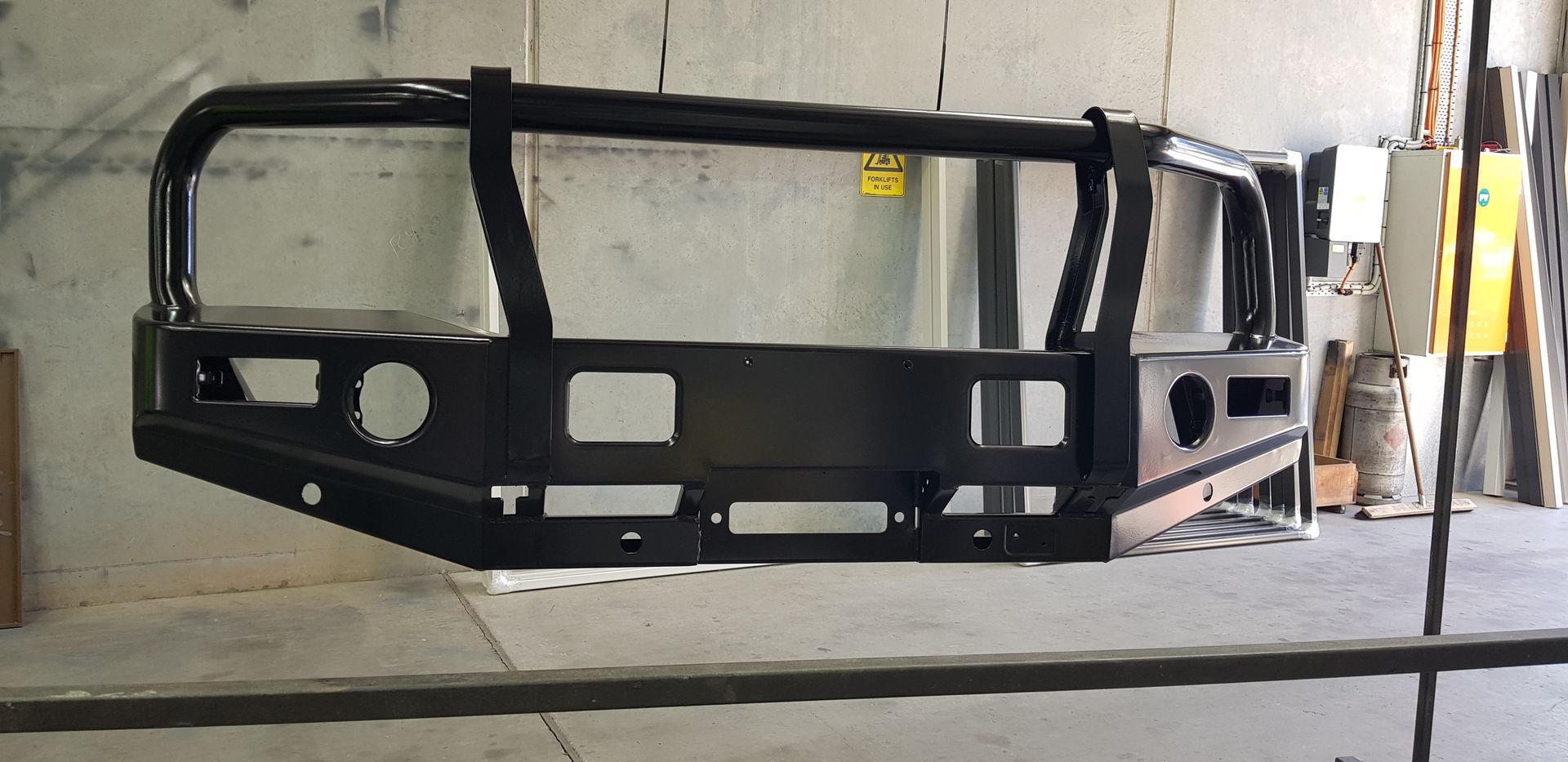 A black bumper is sitting on a metal bar in a garage.