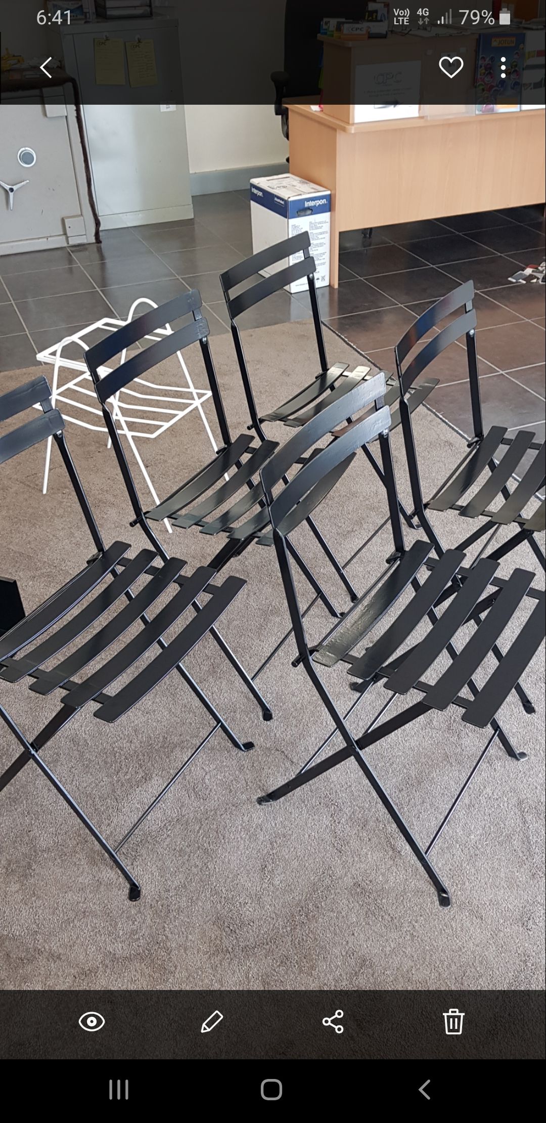 A row of folding chairs are sitting on a carpet in a room.